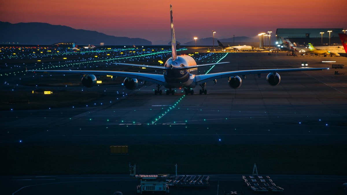 Aircraft taxiing at dusk across illuminated taxiway centreline lighting